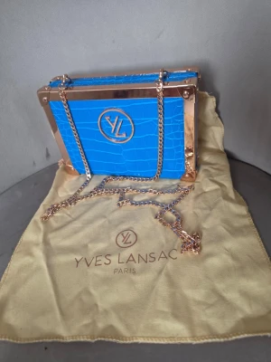 Yves lansac blå väska - Snygg blå kuvertväska från Yves Lansac, det är jättebra skick inte använt så mkt. Köptes för 500kr 