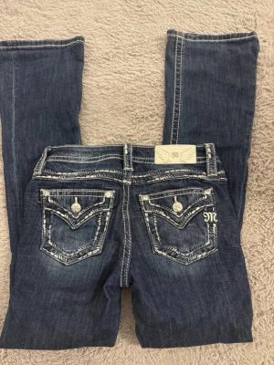 Mörkblå miss me jeans med broderade fickor - Säljer ett par mörkblå miss me jeans med snygga kontrastsömmar och broderade bakfickor. 