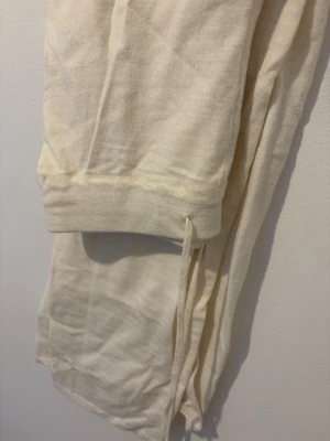 Krämvita mjukisbyxor  - Säljer ett par krämvita  mjukisbyxor och stretchigt material. De har resår i midjan och mudd vid benslutet för en skön passform. Perfekta att mysa i hemma eller styla med en oversized tröja. Passar dig som gillar enkel och clean stil.