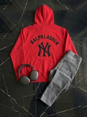 Sällsynt Röd hoodie Ralph Lauren x NY Yankees - Snygg röd hoodie från Ralph Lauren i samarbete med New York Yankees. Stor svart Yankees-logga på ryggen och mindre logga på bröstet. Klassisk huva med vita snören och känguruficka framtill. Perfekt för dig som vill sticka ut med sportig streetstyle. Väldigt eftertraktad och svår att få tag i. 