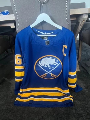 Rasmus Dahlin Buffalo sabers hemmatröja - Helt ny Rasmus Dahlin tröja från säsongerna 24/25 och 25/26 (samma hemmatröja båda säsongerna). Storlek M, inköpt i Buffalo, skriv vid eventuella frågor. NHL hockeytröja. Märke= authentic pro.