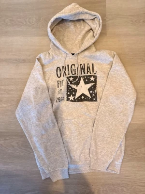 Grå hoodie  - Snygg ljusgrå hoodie från scndi. Hoodien har långa ärmar och mjukt material, perfekt för chill dagar. Den är knappt använd för köpte en storlek för liten kanske 4-5 gånger så finns inga defekter bara att höra av er!