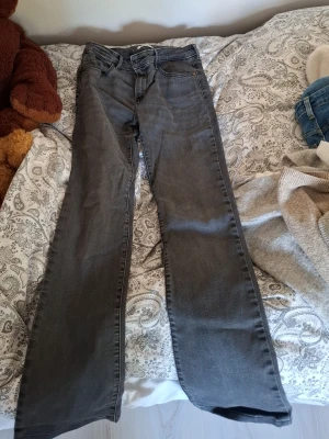 Mörkgrå bootcut jeans  - Mörkgrå mid waist bootcut jeans från wrangler med mönster på fickorna