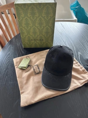 (Äkta) Gucci jumbo keps - Snygg svart keps från Gucci med det klassiska GG-monogrammet ton-i-ton över hela kepsen. Tillverkad i canvasmaterial med böjd skärm och justerbar rem bak. Perfekt accessoar för en trendig och exklusiv look. Nytt pris 5000kr från GUCCI MITT PRIS ENDAST 1300kr KOMMER UTAN TILLBEHÖR. 10/10