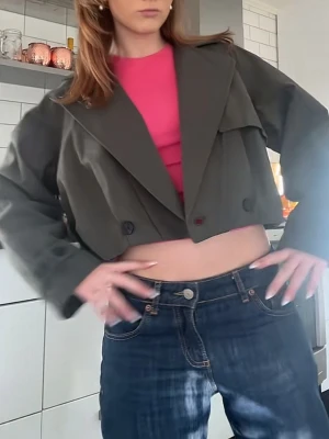 Olivgrön trenchcoat från beshka  - Säljer min slutsålda olivgröna trenchcoat från beshka, den har en omlott knytning (den är oknäppt på bilderna) skickar fler bilder vid behov! den är använd men har inga defekter, nypris 749 kr 