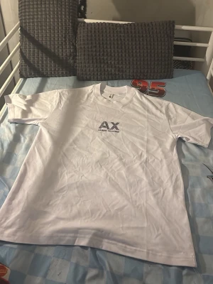 Vit t-shirt från Armani Exchange - Säljer en stilren vit t-shirt från Armani Exchange med logga tryckt på bröstet. Klassisk passform med rund hals och korta ärmar. Perfekt till jeans eller shorts för en clean look.