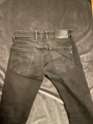 Replay jeans  - Snygga svarta slim fit jeans med fem fickor och klassiska sömmar. Jeansen har en läderpatch bak i midjan och diskreta detaljer på bakfickorna. Perfekta för dig som gillar en clean och stilren look.