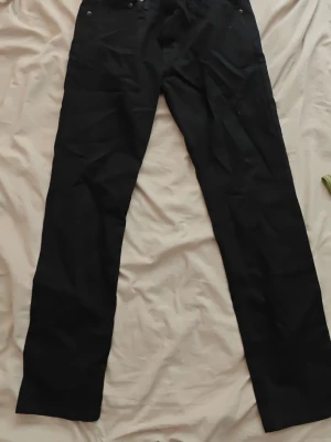 Levi's jeans - Säljer ett par svarta jeans med rak passform och klassisk femficksdesign. Jeansen har bälteshällor och knappgylf. Perfekta för dig som gillar en clean och stilren look.