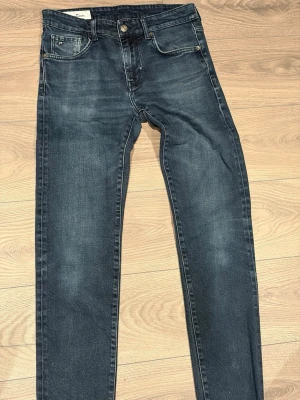 Mörkblå slim jeans med stretch från j Lindeberg  - Snygga mörkblå jeans i slim fit med klassisk femficksdesign och lätt tvättade detaljer. Jeansen har en bekväm passform och är tillverkade i stretchig bomull för extra komfort. Perfekta till vardagslooken och enkla att matcha med olika stilar.