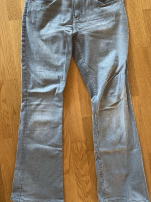Ljusgrå bootcut jeans  - Snygga ljusgråa low/mid rise med bootcut-ben och klassisk femficksdesign. Tillverkade i stretchigt material som ger en bekväm passform. Perfekta för dig som vill ha en avslappnad men trendig stil. Jeansen säljs pga att de inte kommer till användning längre. Ett litet hål har uppstått på byxornas baksida men är lagat, bild finns.