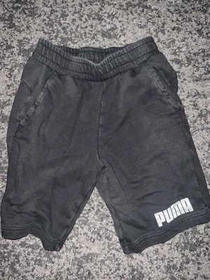 Svarta shorts från Puma - Svarta mjuka shorts från Puma med resår i midjan och två sidofickor. Puma-logga i vitt på ena benet. Perfekta för chill dagar eller träning. Tillverkade i ett bekvämt bomullsmaterial.
