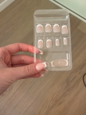 Press-on naglar med fransk manikyr - Säljer ett set press-on naglar i klassisk fransk manikyrstil. Naglarna är ljusrosa med vit tipp och har en oval form. Perfekta för dig som vill ha snygga naglar snabbt och enkelt. Kommer i plastförpackning med flera storlekar. Alla storlekar finns tyvärr inte vissa är slut så jag säljer de billigt 