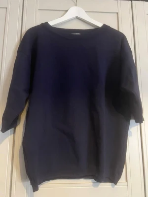 Mörkblå oversized tröja - En enkel och stilren mörkblå tröja med oversized passform och trekvartsärmar. Tröjan har rund halsringning och är gjord i ett mjukt material som känns skönt mot huden. Perfekt för en avslappnad look.
