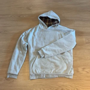 Grå hoodie med rutigt foder i huvan - Kan våndas ut och in för helruttig look