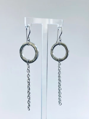 Silvriga örhängen i stål med ring och kedja - Snygga örhängen i silverfärgat stål med rund ring och hängande kedja. Modern och stilren design som ger en cool touch till din look. Perfekta för dig som gillar minimalistiska accessoarer.