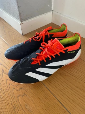 Adidas Predator fotbollsskor svart/röd - adidas Predator Elite Laceless AG – Solar Energy  Säljer ett par adidas Predator Elite Laceless AG i storlek EU 42 2/3 (UK 8,5).  Skorna är använda och har därför vissa tecken på användning:  * Dobbarna är lite slitna, men fortfarande i bra skick. * Det finns lite smuts på skorna. * Snörena är något slitna och smutsiga efter användning. * I övrigt är skorna i bra skick och fullt användbara.  Se bilderna för exakt skick. Säljs i befintligt skick. Nypris ligger runt 2000kr.