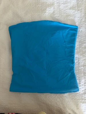 Två tubtoppar - Säljer två bandeautoppar i stretchigt material, en i klarblå och en i ljusgul färg. Perfekta att styla till jeans eller kjol för en enkel och trendig look. Topparna är axelbandslösa och har en tight passform.