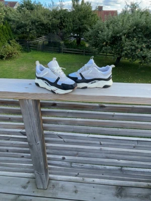 Chunky vita och svarta sneakers - Säljer ett par chunky sneakers i vitt och svart med grå detaljer. Skorna har en tjock sula och ovandel i mesh och syntetmaterial. Snygg sportig look med coola kontraster och perforerade partier. Perfekta för dig som gillar streetstyle och vill sticka ut.