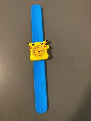 Två färgglada slap-on barnklockor - Säljer två slap-on armbandsklockor för barn. En blå med Pikachu-motiv och en rosa med motiv av två tecknade tjejer. Klockorna har tydliga urtavlor och färgglada band som är lätta att ta på och av. Perfekt accessoar för dig som gillar lekfull stil. 115 kr /st , nya klocka med nya batterier 