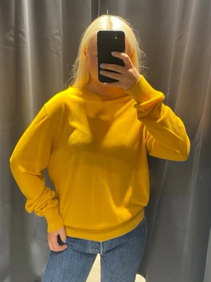 Acne Gul långärmad tröja   - Snygg gul långärmad tröja från Acne Studios i mjukt och tunt material. Tröjan har rund halsringning, avslappnad passform och ribbade muddar vid ärmslut och nederkant. Perfekt att styla med jeans för en trendig look.