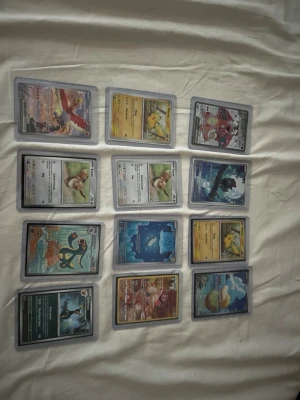 Samling Pokémonkort i plastfickor - Säljer en samling Pokémonkort med olika motiv och färger, bland annat Pikachu, Eevee och flera andra populära Pokémon. Korten är i standardstorlek och ligger i genomskinliga plastfickor. Perfekt för dig som vill utöka din samling eller börja samla Pokémonkort.