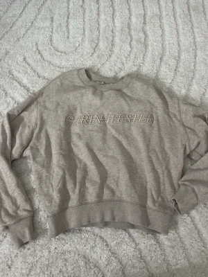 Beige sweatshirt Carin Wester XS - Säljer en beige sweatshirt från Carin Wester i storlek XS. Tröjan har rund halsringning, ribbade muddar vid ärmar och nederkant samt broderad logga framtill. Perfekt för en avslappnad och trendig look. Materialet känns mjukt och skönt mot huden.