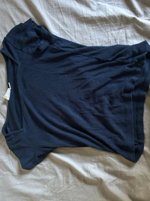 Mörkblå enkel kortärmad topp - En basic mörkblå topp med rund hals och korta ärmar. Tillverkad i mjukt material som känns skönt mot huden. Perfekt att matcha med jeans eller kjol för en clean look.