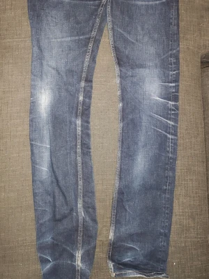Mörkblå slim fit jeans - Snygga mörkblå slim fit jeans med slitningar och ljusa tvätteffekter på låren och knäna. Klassisk femficksmodell med kontrastsömmar och rak passform. Perfekta för en avslappnad och trendig look.