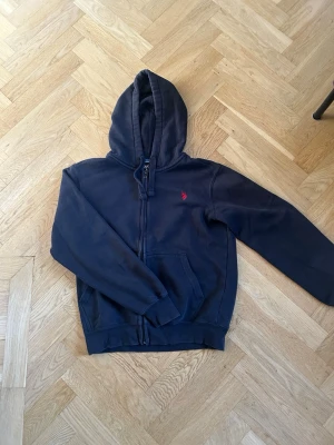 Mörkblå Ralph lauren  hoodie med dragkedja - Snygg mörkblå hoodie med dragkedja och huva. Klassisk passform med två fickor framtill och justerbara snören i huvan. Liten broderad logga på bröstet. Tillverkad i mjukt sweatshirtmaterial som är skönt mot huden. Märket är U.S.POLO ASSN. Storlek S men hade fungerat som M Finns även likande plagg i profilen. Hör gärna av dig för frågor eller bundel deals😊😉⭐️