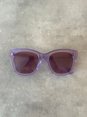 Chimi core 07 light purple - Chimi solglasögon med transparent lila båge och mörka glas. Bågarna har en bred, fyrkantig form som ger en trendig look. Perfekta för att addera färg till din outfit under soliga dagar.