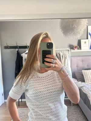 Vit virkad kortärmad tröja - Säljer en vit virkad tröja med korta ärmar. Tröjan har ett luftigt, hålmönstrat material som ger en fräsch och trendig look. Perfekt att styla med jeans eller kjol för en avslappnad vibe.