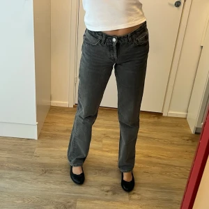 Grå raka jeans med låg midja - Grå jeans med rak passform och låg midja. Jeansen har klassiska fem fickor och stängs med knapp och dragkedja. Något slitna vid låren men inget som syns 