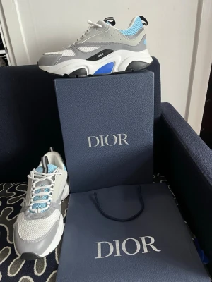 Dior B22 sneakers grå/blå - Säljer ett par Dior B22 sneakers i grått, vitt, svart och blått.  I storlek 45