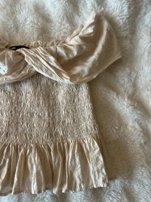 offshoulder topp  - Supersöt beige offshoulder topp med tightare midja och volangkant nedtill. Jätte fin när som!!