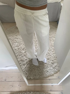 Vita linnebyxor med resårmidja - Säljer ett par vita linnebyxor med avslappnad passform och resår i midja. Byxorna har raka ben och sidofickor. Perfekta för en chill och luftig stil under varma dagar.