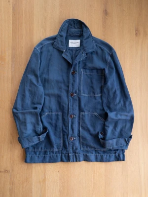 Blue Chore Jacket, size M - Snygg blå overshirt i bomull med tre stora utanpåliggande fickor och knappar framtill. Avslappnad passform och synliga sömmar ger en cool vintagekänsla. Perfekt att bära öppen eller stängd över en t-shirt.