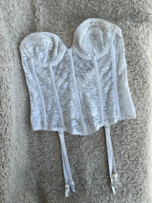Fin korsett i vitt och spets, XS. 36A. Vintage - Finaste korsetten i vit spets med strumpeband. Något beige på spännen på insidan, den var så när jag fick den. Har även några ljusgula fläckar på ett strumpeband, se gärna bild! Vet ej om det är på fler. Storlek 36A enligt tag, passar en XS.