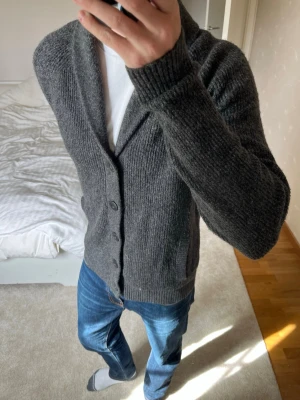 Mörkgrå stickad kofta med knappar från Hollister - Säljer en sjukt fet stickad cardigan från Hollister gjord i ett väldigt skönt material. Cardiganen är i ett väldigt fint skick utan defekter! ✌🏼——————————————————————————                                                                      📐| Storlek: M                                                           👖| Märke: Hollister                                                🔎| Skick: Mycket Fint!                                                     ✍🏻| Skriv om du har några frågor