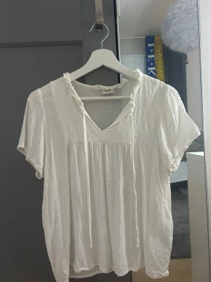 Vit blus med knytband - Säljer en superfin vit blus med korta ärmar och knytband vid halsen, storleken är 38 men skulle säga att den är som en xs, skicka gärna prisförslag!!❣️