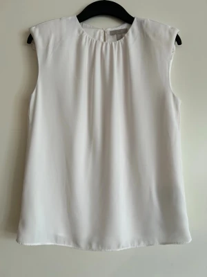 Kortärmad blus med axelvaddar - Väldigt fin blus med kort ärm och axelvaddar! Skapar en väldigt snygg look.   Längd: ca 62-63 cm