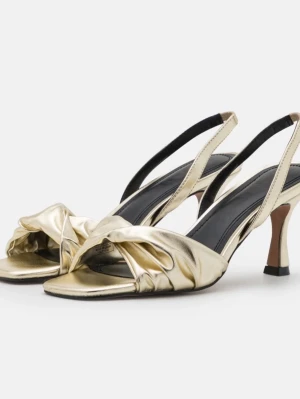 Guldiga klackskor  - Säljer ett par glansiga sandaletter i guld med öppen tå och elegant knutdetalj framtill. Skorna har smal klack och justerbar slingback-rem. Tillverkade i ett metallic-liknande material som ger en lyxig känsla och passar perfekt till sommarens outfits.