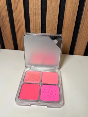 Huda Beauty fyrfärgad rougepalett - Helt nytt Rougepalett från Huda Beauty med fyra olika nyanser i rosa och korall. Paletten har en transparent plastförpackning med spegeleffekt på locket och innehåller både matta och skimrande puderrouger. Perfekt för att skapa olika blush-looks.