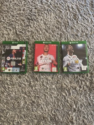 FIFA 18, 20 & 21 till Xbox One - Säljer tre FIFA-spel till Xbox One: FIFA 18, FIFA 20 och FIFA 21. Alla spel har gröna plastfodral och omslag med fotbollsspelare på framsidan. Perfekt för dig som gillar fotbollsspel och vill utöka din samling. 475 för alla