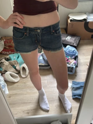 Mörkblå jeansshorts - Säljer ett par mörkblå jeansshorts med fransig, rå kant nertill. Klassisk femficksmodell med knapp och dragkedja framtill. Perfekta till sommaren och har en lågmidjad passform. Snygga att matcha med crop tops eller hoodies. Ord pris 399 från weekday! PASSAR MIG SOM HAR XS-S