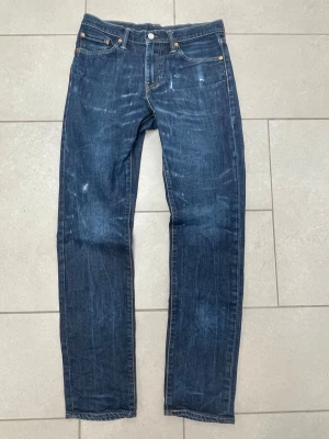 Levi's 511 - Klassiska mörkblå jeans från Levi's med slim ben och femficksmodell. Jeansen har subtila slitningar och kontrastsömmar, samt den ikoniska läderpatchen bak i midjan. Tillverkade i robust denim som ger en tidlös look. Modellen är 511 och storleken w30 l34