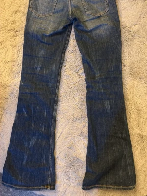 Blå bootcut jeans Cheap monday  - Snygga blå bootcut jeans med tydliga slitningar framtill och baktill. Jeansen har klassisk femficksdesign, låg midja och är tillverkade i denim. Perfekta för en avslappnad och trendig look.