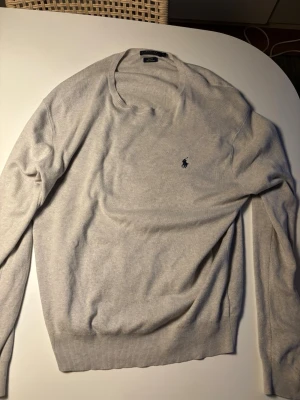 Ralph Lauren Tröja grå  - Riktigt snygg Ralph Lauren tröja i storlek L slim fit. Skulle dock säga att den passar mer som M. Riktigt snygg ljusgrå färg och perfekt plagg nu inför höstsäsongen. 😊