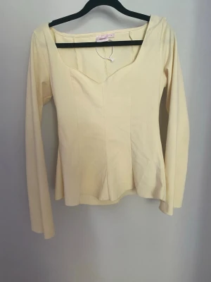 Ljusgul långärmad topp Gina Tricot - Snygg ljusgul långärmad topp från Gina Tricot med v-ringad hals och figurnära passform. Tillverkad i mjukt material som känns skönt mot huden. Perfekt att styla med jeans eller kjol för en trendig look.