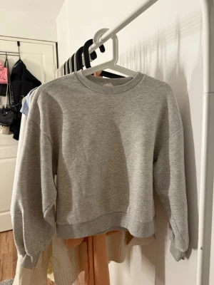 Grå sweatshirt från Gina Tricot - En enkel och stilren grå sweatshirt från Gina Tricot, modell Basically Basics. Tröjan har rund halsringning, ribbade muddar vid ärmslut och nederkant samt en avslappnad passform. 