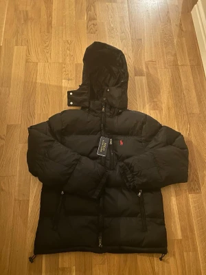Ralph Lauren Jack Svart M | Ralph Lauren Jacka - Snygg och stilren Ralph Lauren Jack i klassisk svart färg, storlek M. Perfekt jacka som passar både till vardags och en mer dressad outfit. Tidlös modell som är lätt att matcha. 🔥  📏 Storlek: M 🎨 Färg: Svart 🏷️ Ralph Lauren 📦 Snabb affär uppskattas!